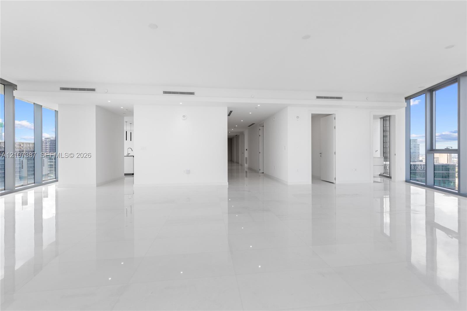 Open-concept interior featuring floor-to-ceiling windows, polished stone-finish flooring, and recessed ceiling lighting
