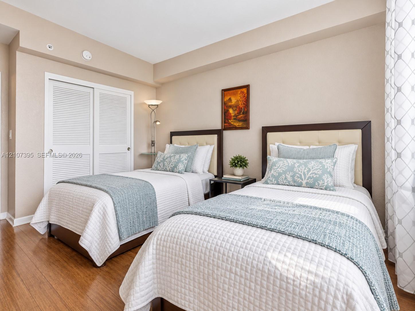 Bedroom featuring wood-finish flooring, neutral wall paint, and a sliding louvered-panel closet door