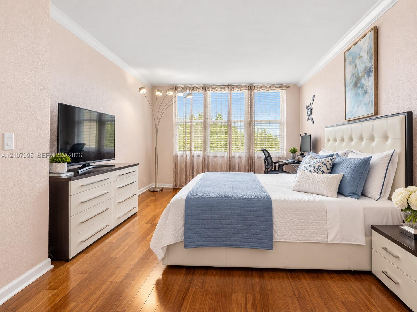 Room featuring polished wood-finish flooring, crown molding, and large windows with horizontal blinds