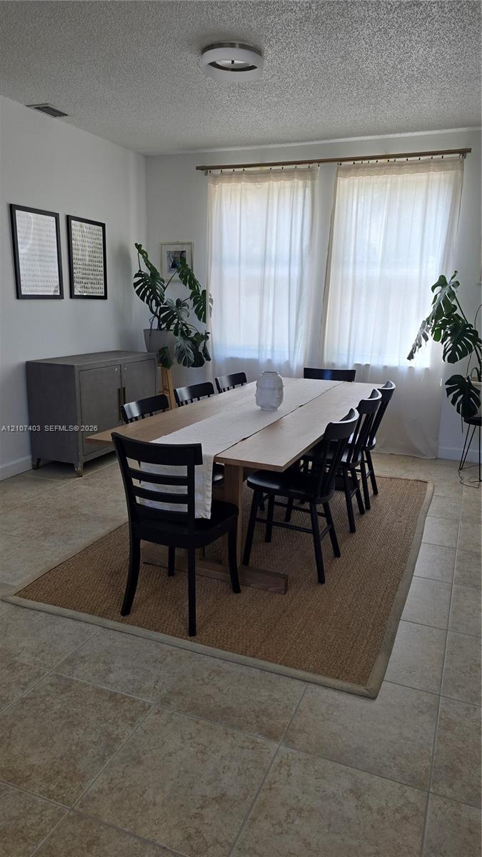 Neutral tile flooring, dual large-format windows, and a central flush-mount ceiling fixture Neutral tile flooring, dual large-format windows, and a central flush-mount ceiling fixture