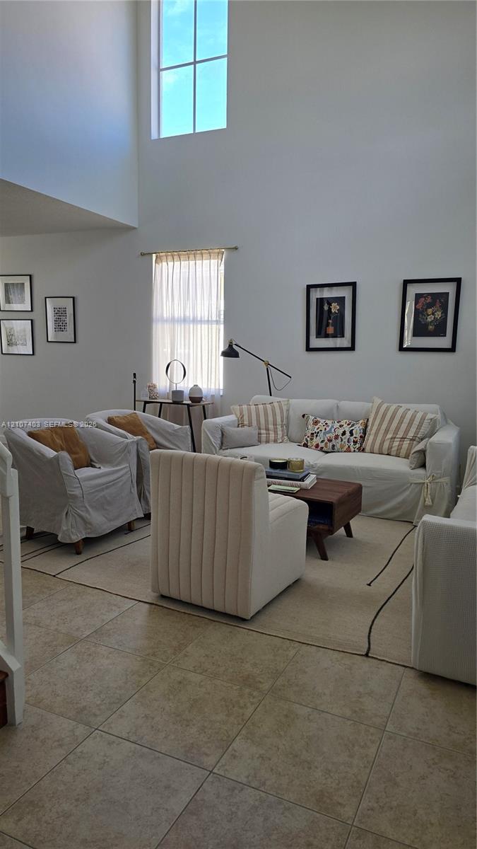 Double-height ceiling featuring large vertical windows and neutral tile flooring Double-height ceiling featuring large vertical windows and neutral tile flooring