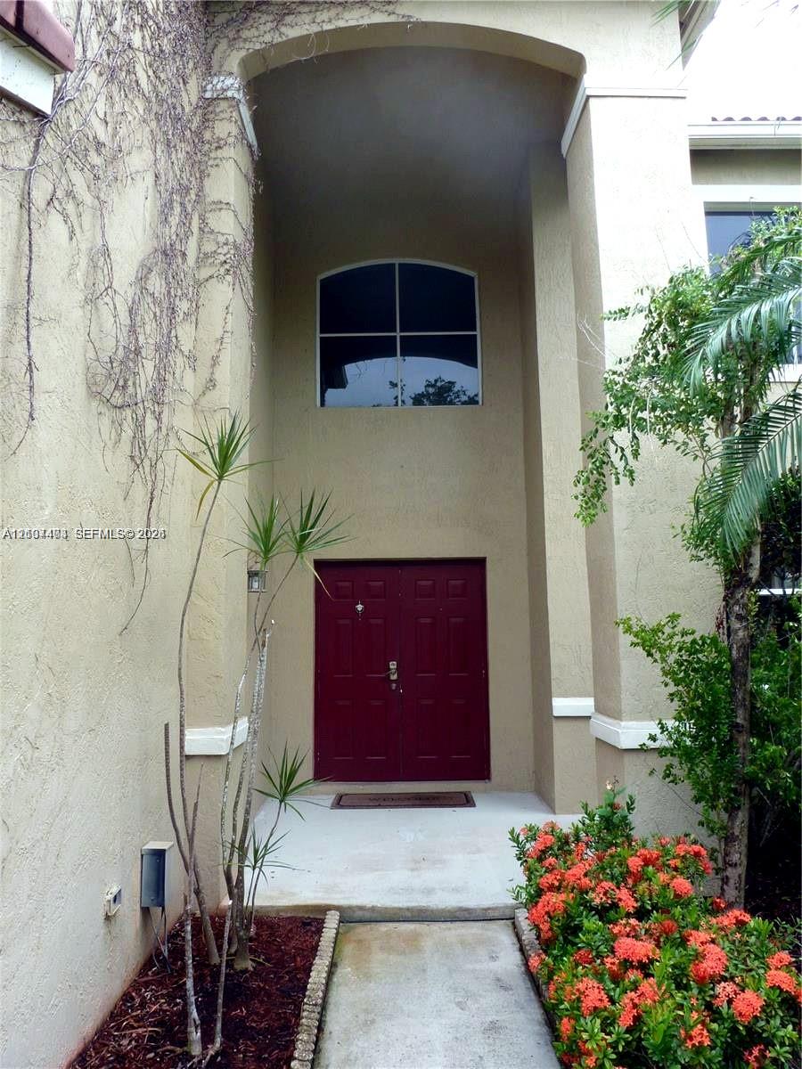 Stucco exterior entrance featuring a double door entry, covered recessed portico, arched transom window, and concrete walkway Stucco exterior entrance featuring a double door entry, covered recessed portico, arched transom window, and concrete walkway