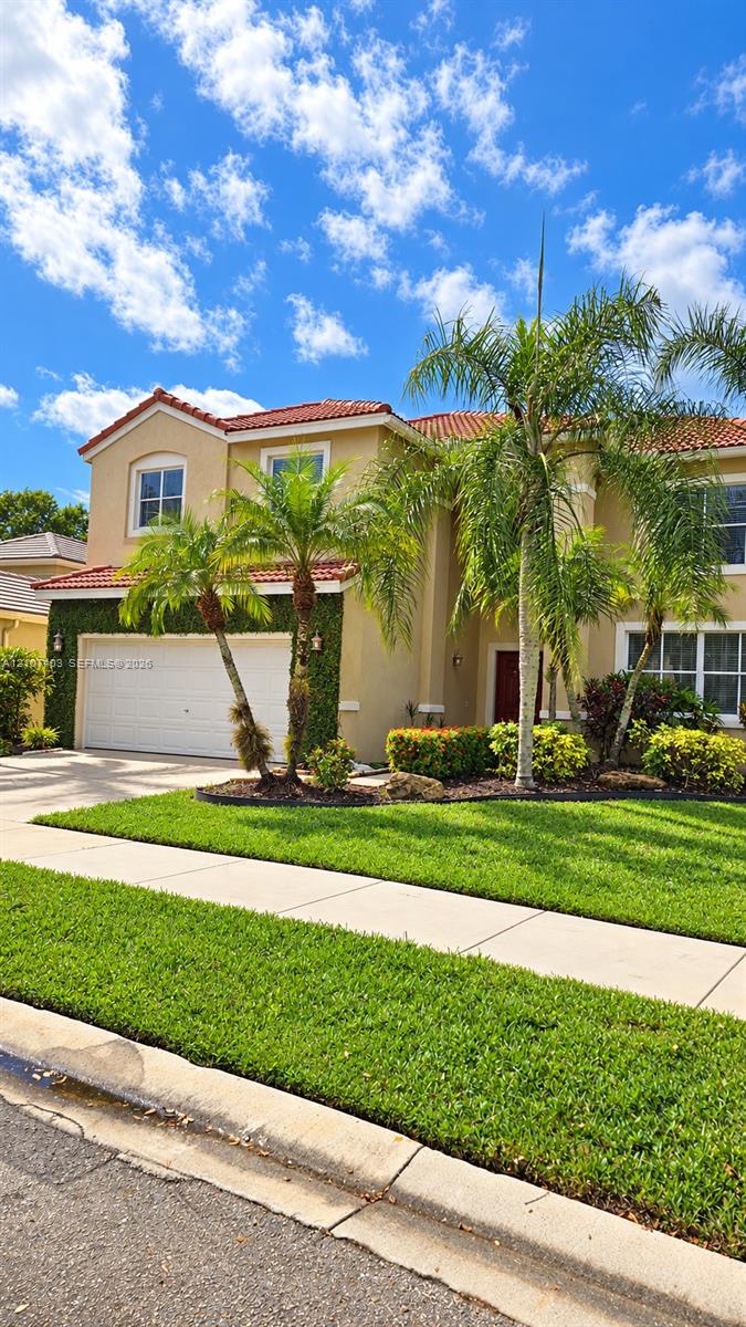Two-story residence featuring a terracotta-tiled roof, stucco exterior, multi-pane windows, and a paved driveway leading to an attached two-car garage Two-story residence featuring a terracotta-tiled roof, stucco exterior, multi-pane windows, and a paved driveway leading to an attached two-car garage