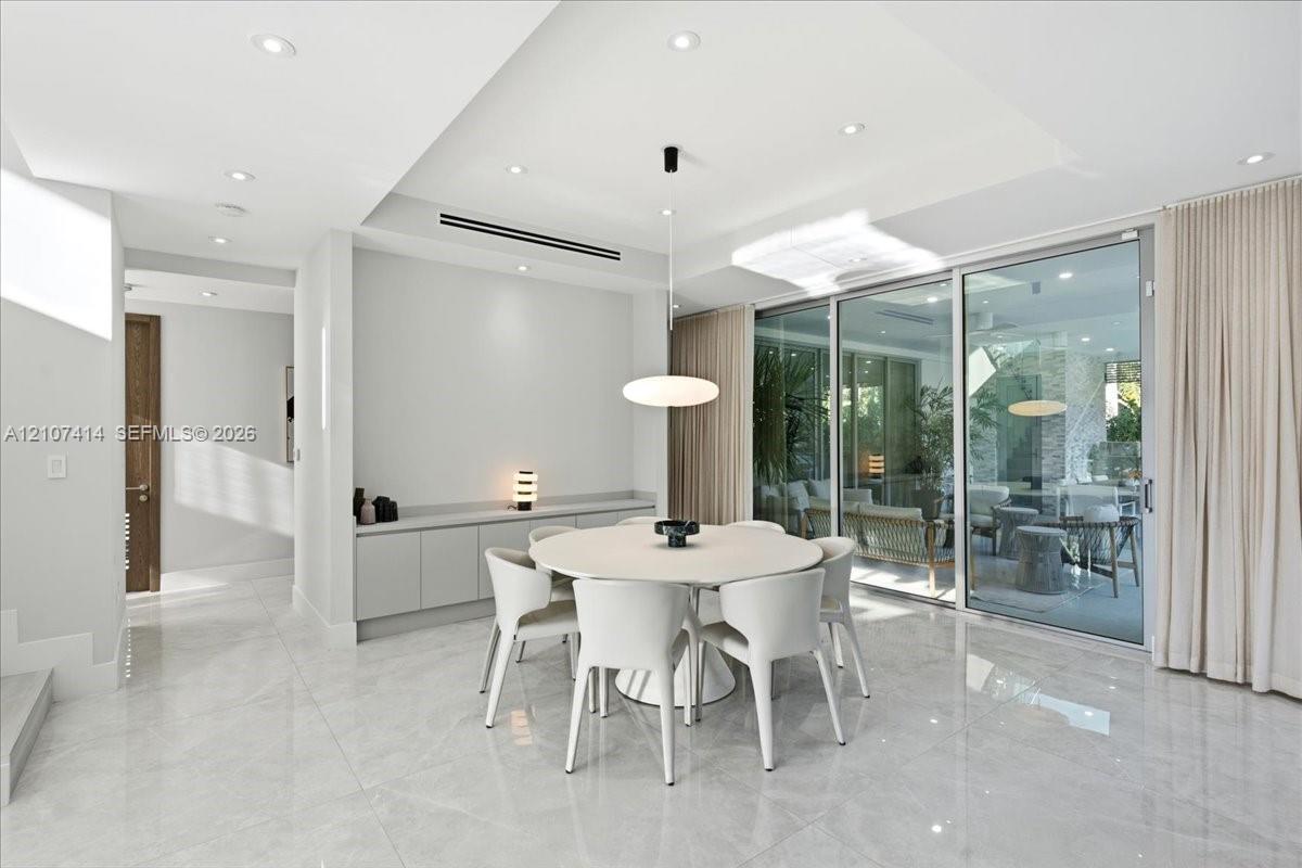 Polished stone-finish flooring, built-in wall cabinetry, recessed ceiling lighting, a modern pendant light fixture, and floor-to-ceiling sliding glass doors