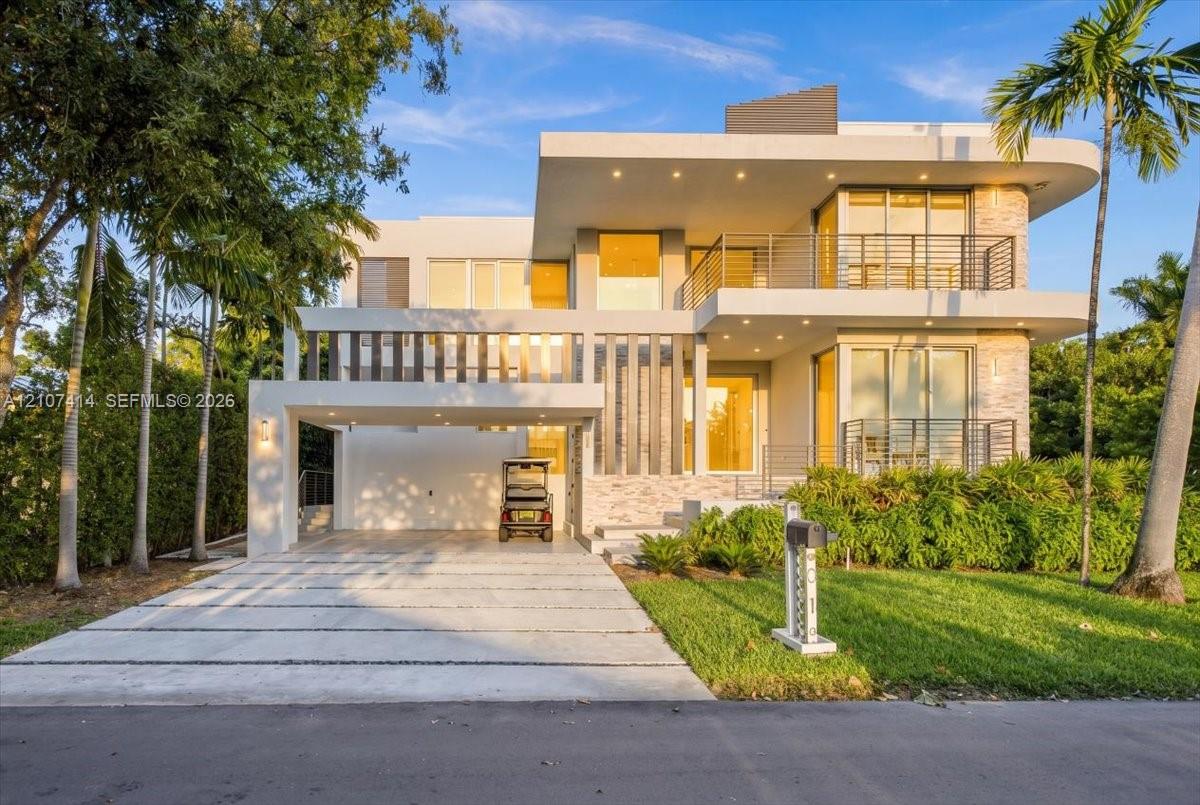 Modern multi-level exterior featuring smooth white stucco, stacked stone accents, two expansive balconies with metal railings, and a covered carport Modern multi-level exterior featuring smooth white stucco, stacked stone accents, two expansive balconies with metal railings, and a covered carport
