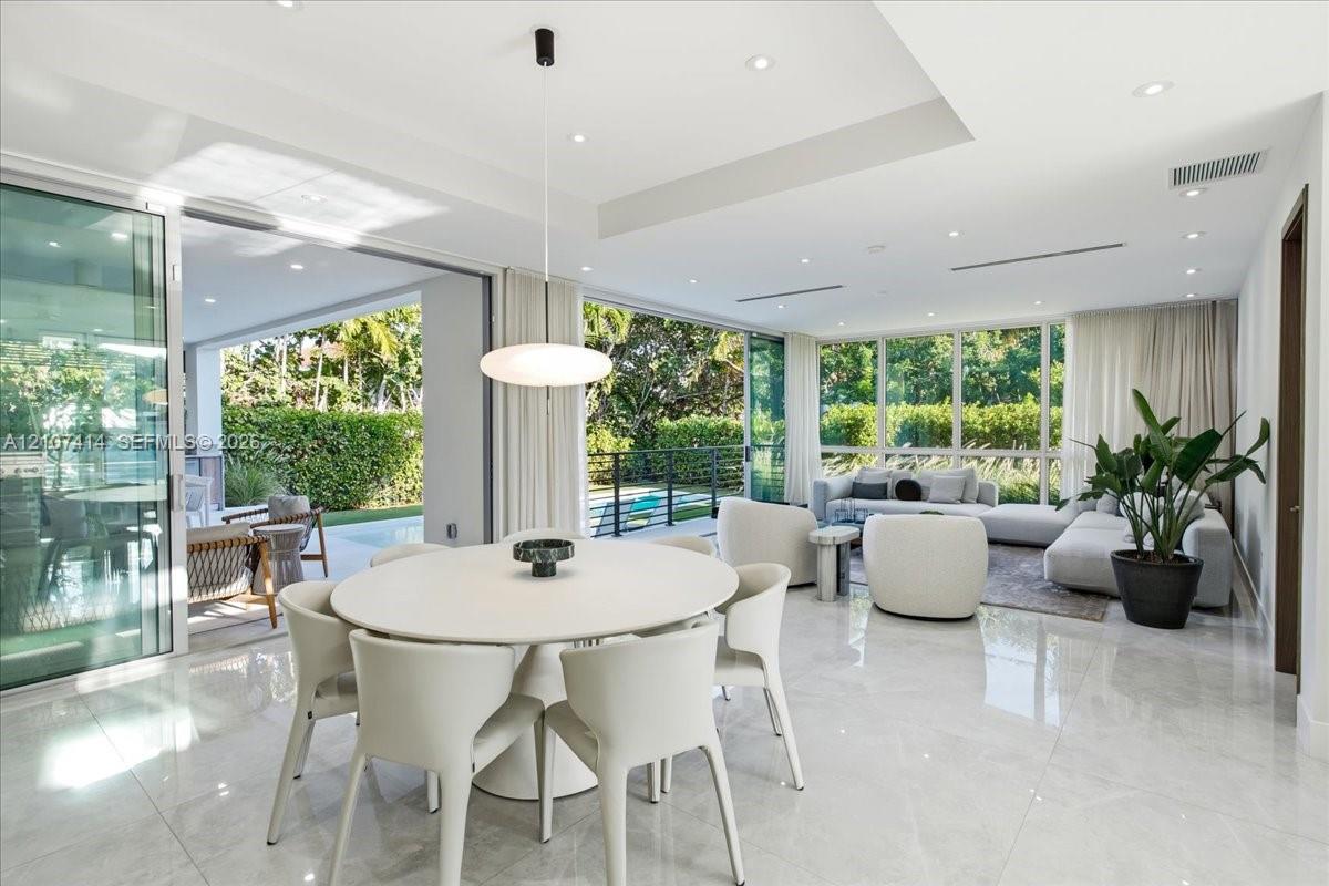 Open-concept living space featuring large-format tile flooring, recessed lighting, a tray ceiling, and floor-to-ceiling glass sliding doors providing exterior access