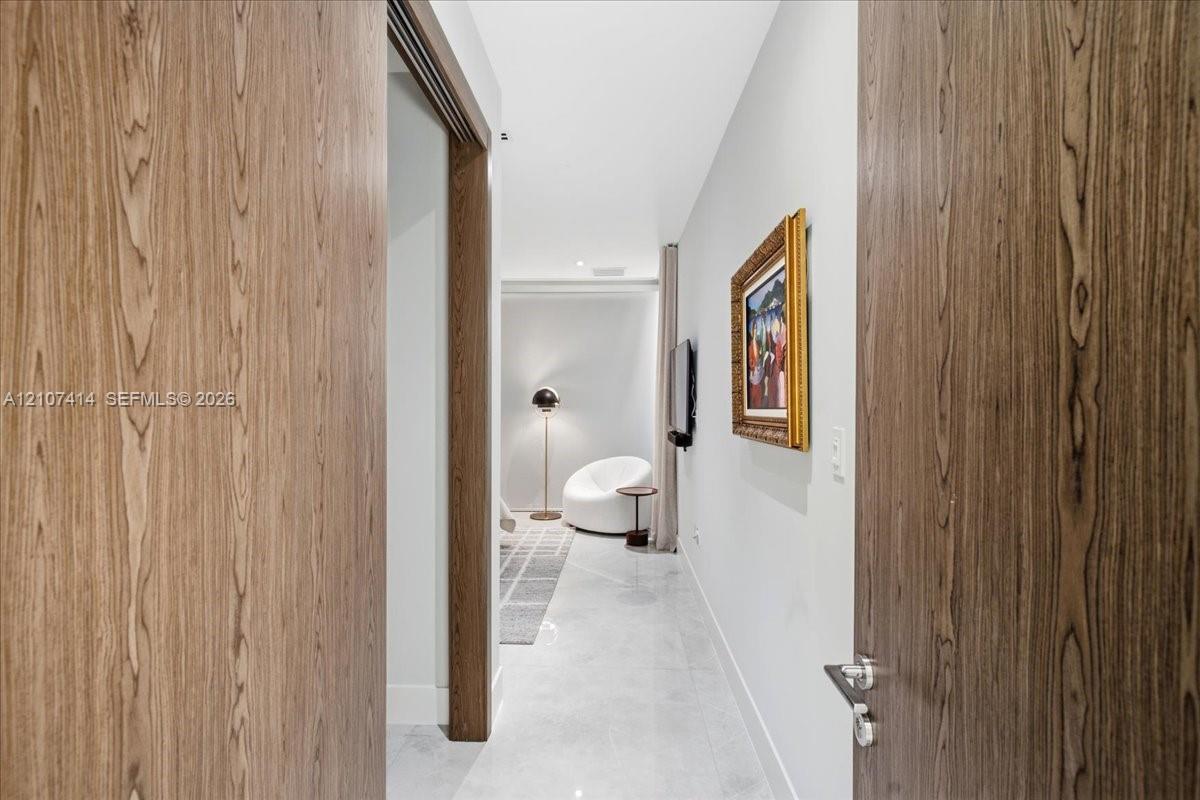 Solid wood-finish doors with brushed nickel lever hardware, polished stone flooring, and recessed ceiling lighting