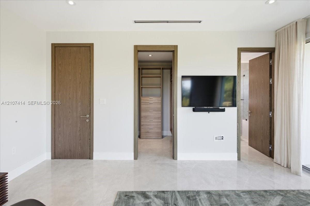 Interior space featuring large-format stone flooring, recessed lighting, and solid wood-finish doors