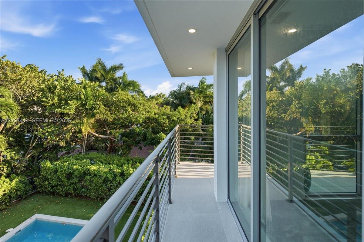 Balcony featuring metal horizontal-rail fencing, recessed ceiling lighting, and large-format sliding glass doors