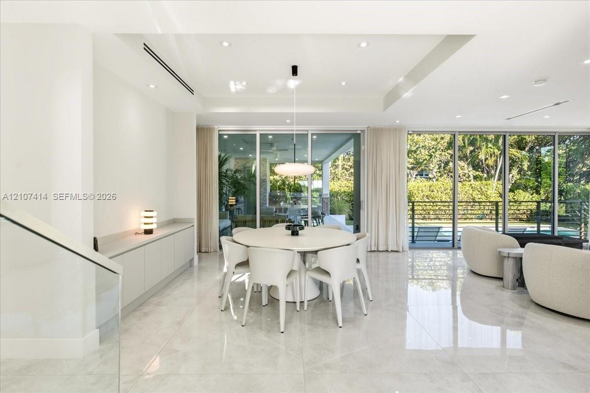 Open-concept interior featuring large-format tile flooring, floor-to-ceiling glass sliding doors, recessed lighting, and custom built-in cabinetry with a stone-top surface