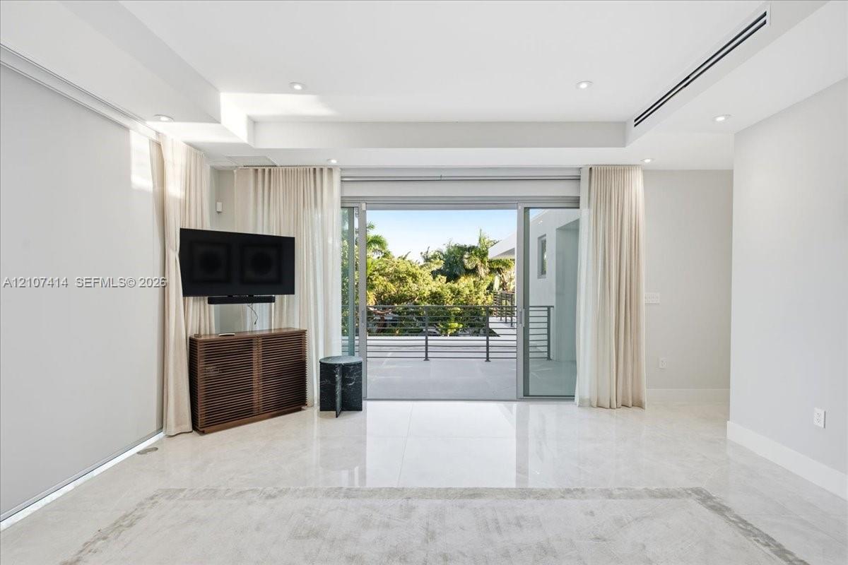 Interior space featuring polished stone flooring, recessed ceiling lighting, a linear HVAC diffuser, and expansive multi-panel sliding glass doors opening to a covered balcony