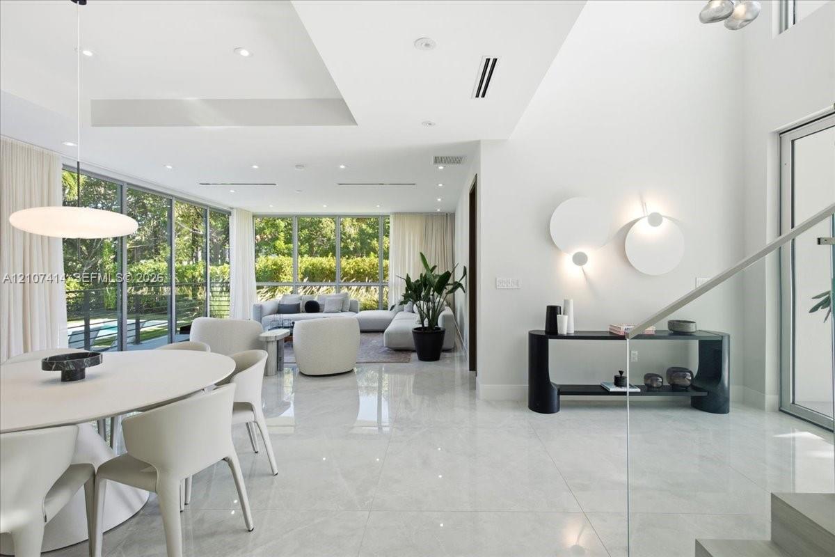 Open-concept interior featuring floor-to-ceiling glass walls, large-format tile flooring, recessed lighting, and sculptural wall-mounted fixtures Open-concept interior featuring floor-to-ceiling glass walls, large-format tile flooring, recessed lighting, and sculptural wall-mounted fixtures