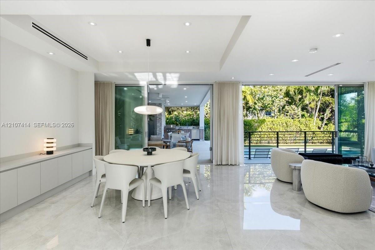 Large-format polished tile flooring, recessed ceiling lighting, built-in floor-to-ceiling cabinetry, and expansive multi-panel sliding glass doors
