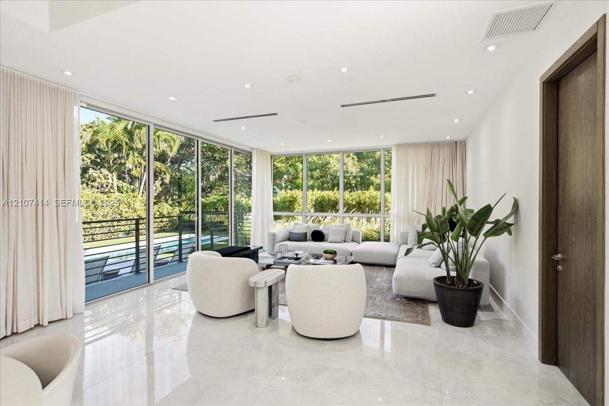 Floor-to-ceiling glass walls, polished stone flooring, recessed ceiling lighting, and wood-finish interior door