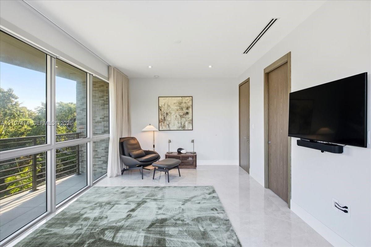 Floor-to-ceiling glass windows, stone flooring, wood-finish interior doors, and a recessed linear ceiling light fixture