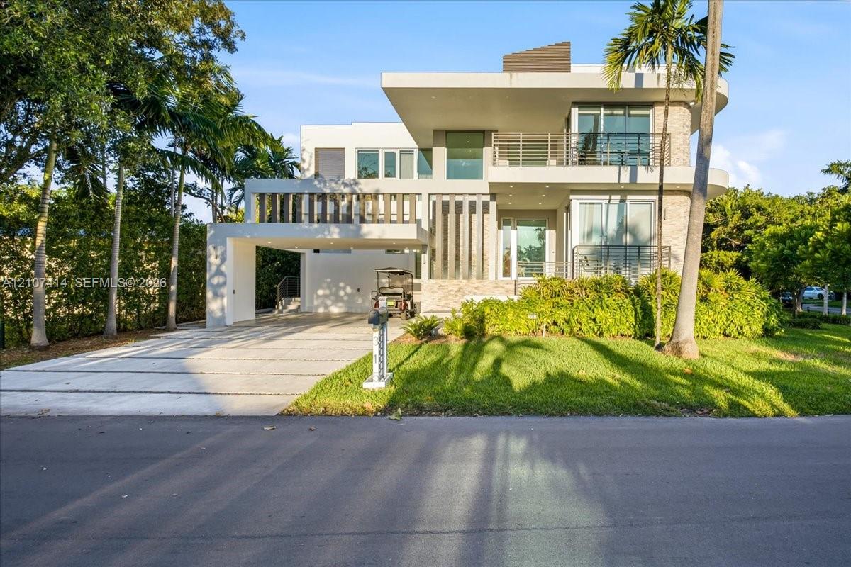 Modern multi-level exterior featuring white stucco facade, stone veneer accents, integrated carport, and elevated balconies with metal railings