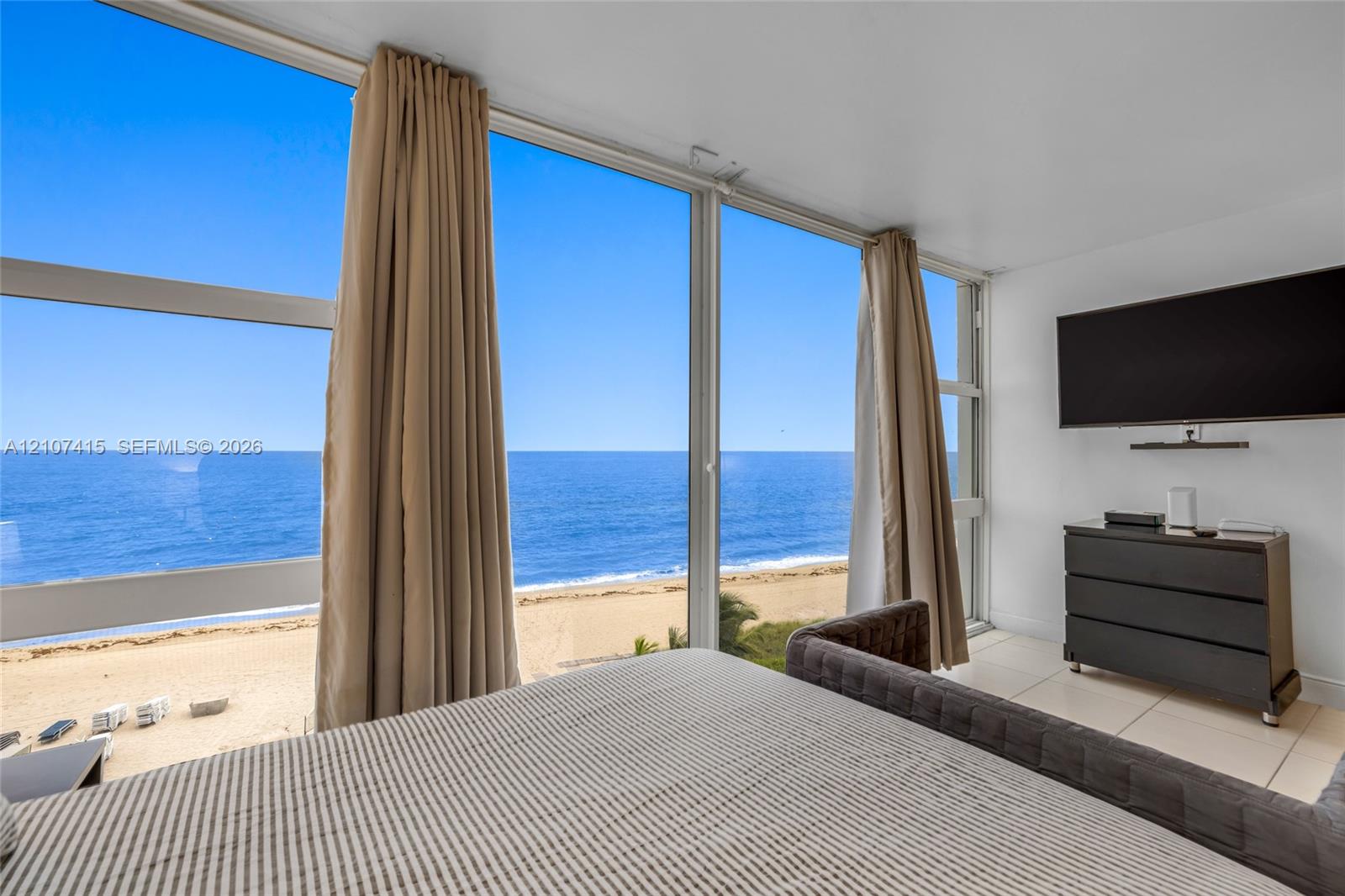 Floor-to-ceiling windows, large-format tile flooring, and coastal scenery