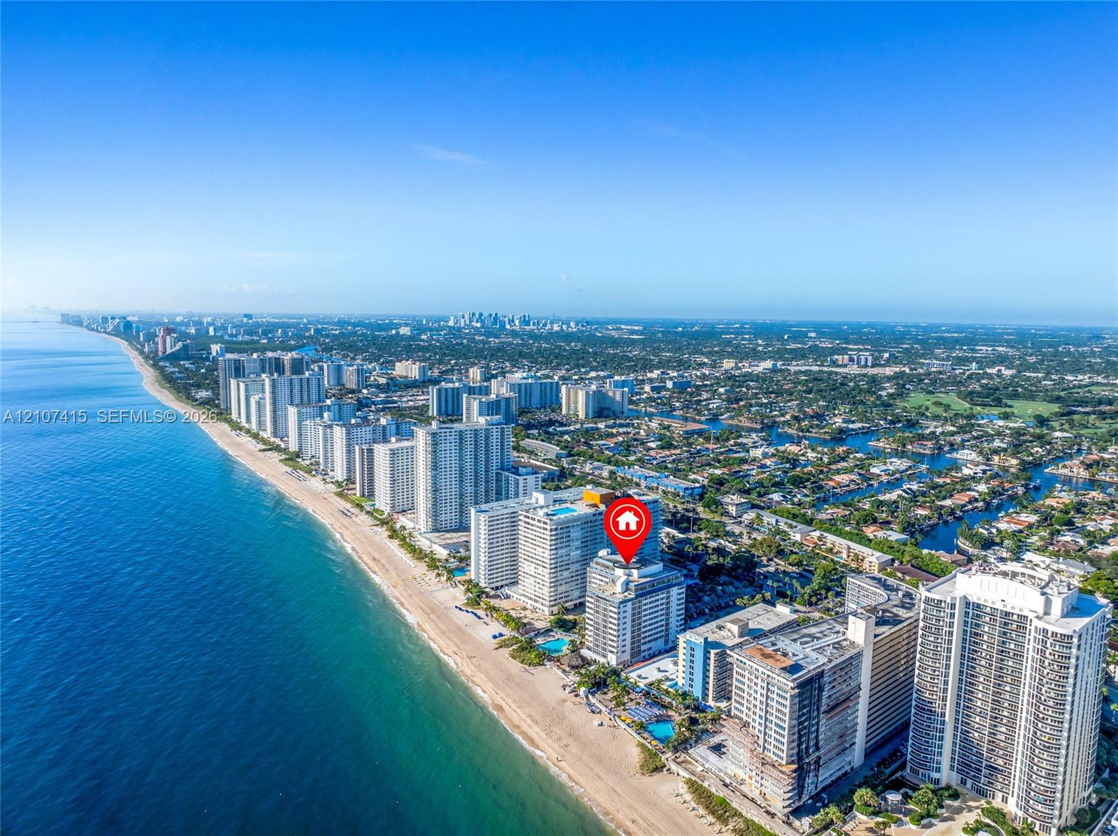 Aerial perspective of coastal high-rise building positioned directly along the shoreline with proximity to oceanfront beaches and urban infrastructure