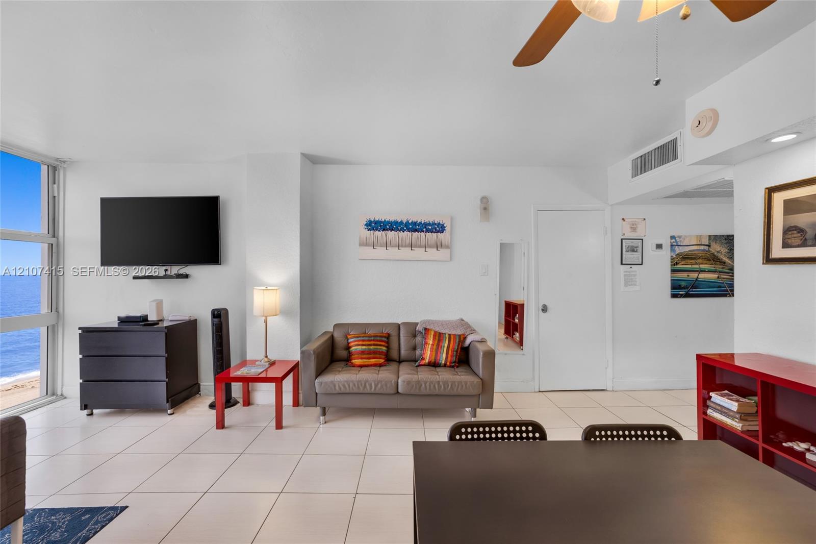 Living area featuring floor-to-ceiling windows, tile flooring, and a ceiling fan