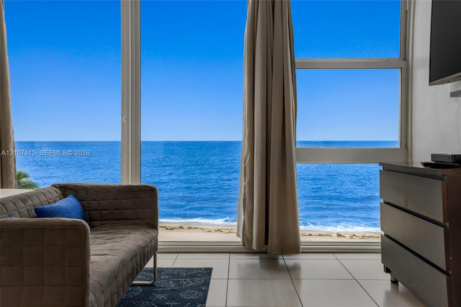 Floor-to-ceiling windows featuring ocean scenery, tile flooring, and a white interior color palette