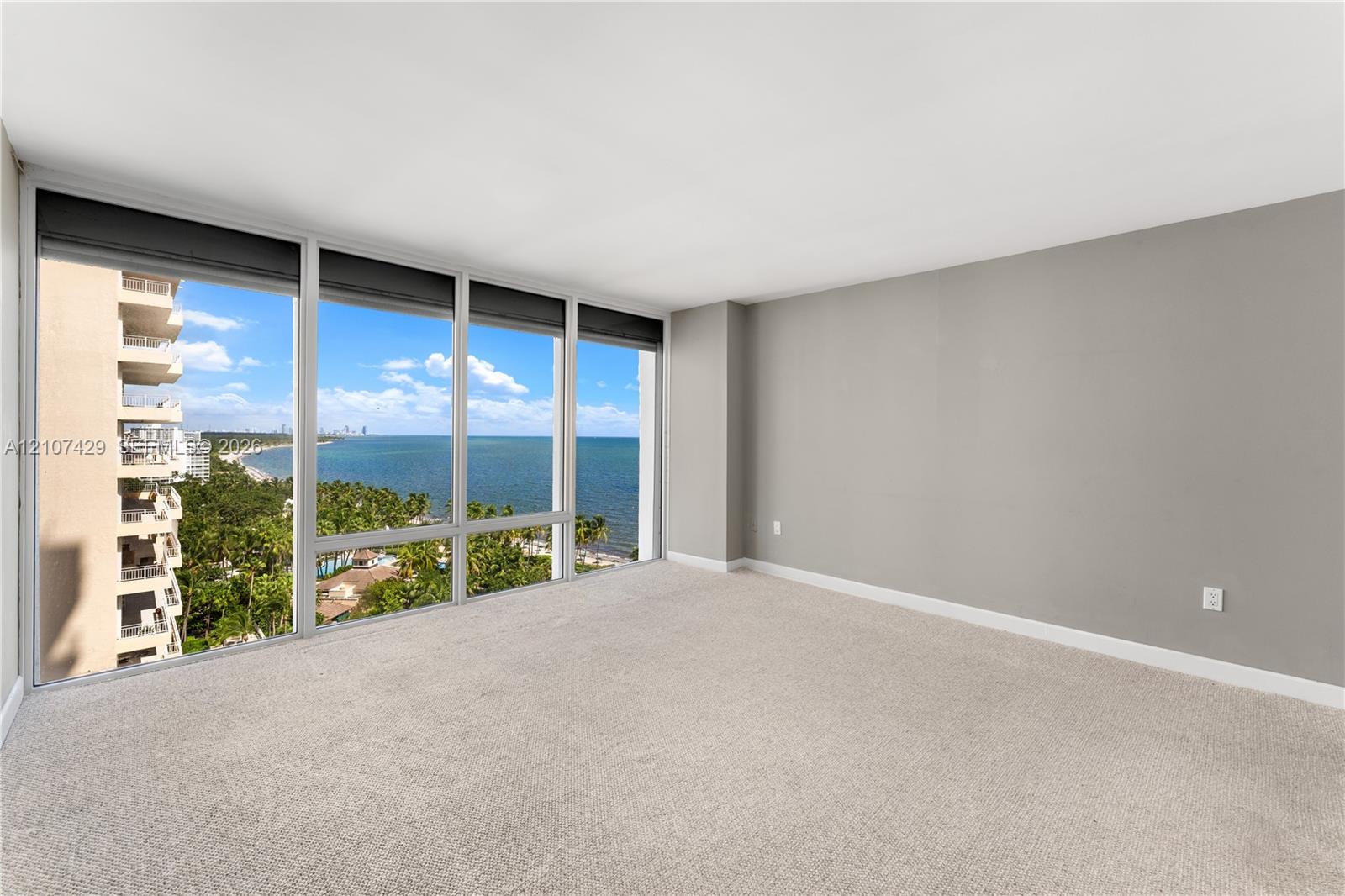 Floor-to-ceiling windows featuring panoramic coastal and ocean scenery, neutral wall tones, and wall-to-wall carpeting