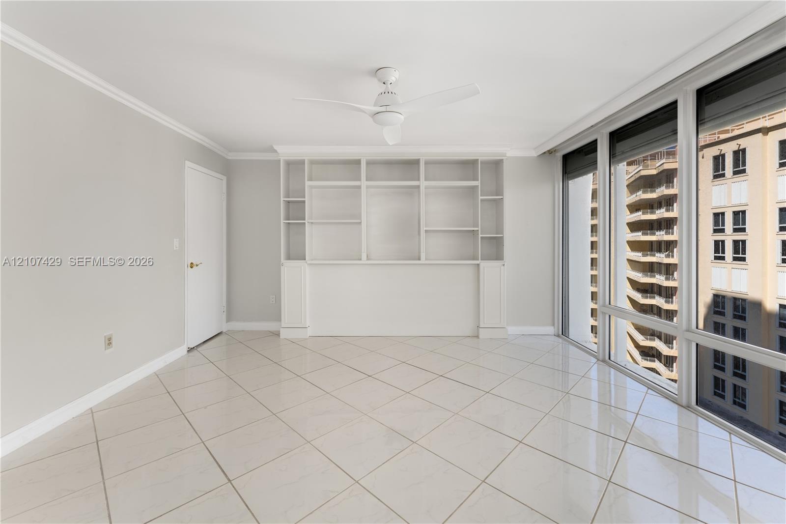 Interior featuring large-format diagonal tile flooring, floor-to-ceiling windows, white built-in shelving, and a ceiling fan