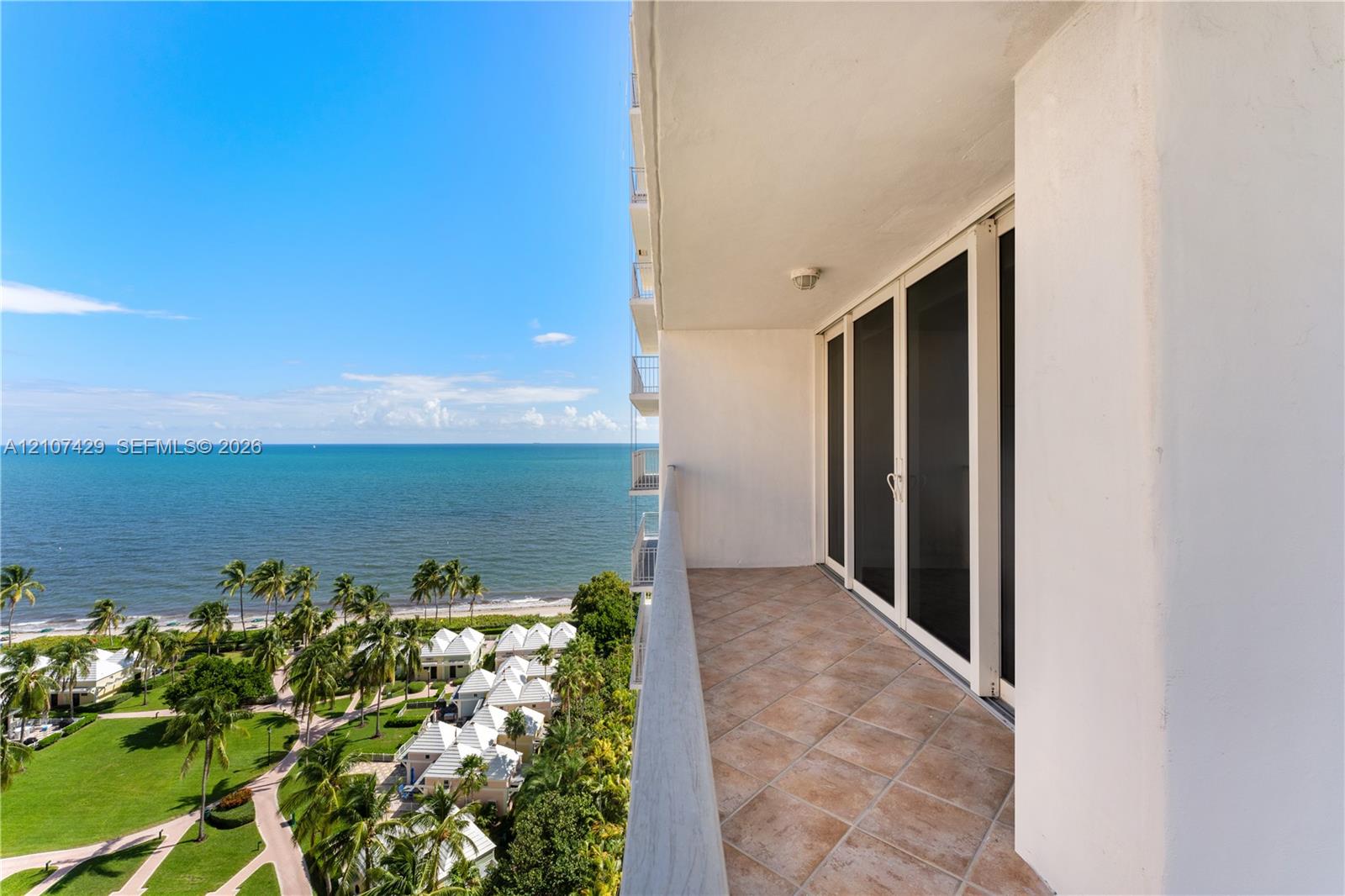 Private covered balcony featuring neutral tile flooring, glass sliding door access, and ocean backdrop