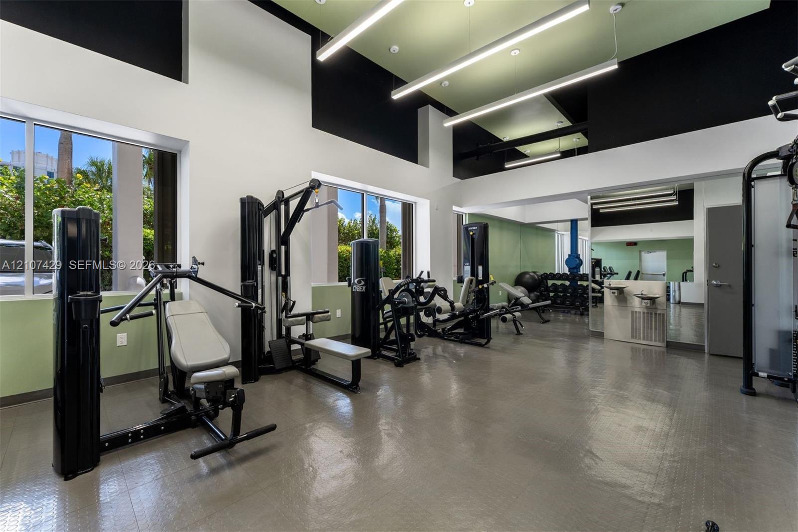 Fitness center featuring high ceilings with integrated linear lighting, large windows, mirrored walls, and durable resilient flooring