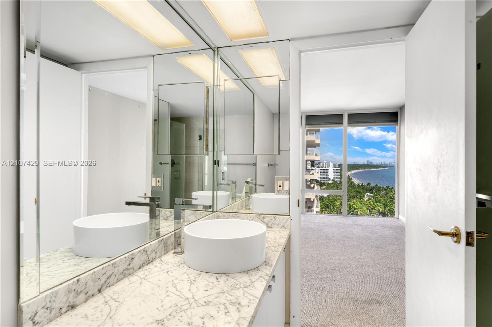 Bathroom featuring dual vessel sinks, stone-patterned vanity countertop, full-height wall mirrors, and recessed ceiling lighting