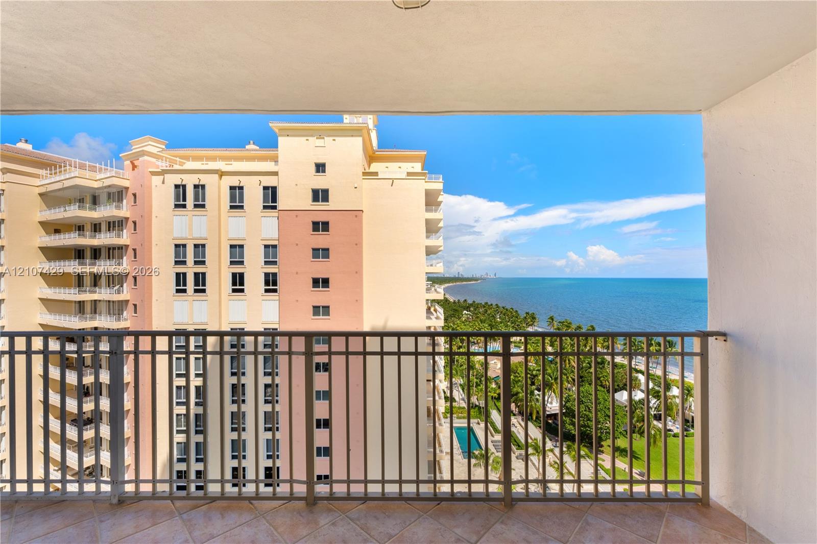 Private balcony featuring tile flooring and a metal railing, providing an elevated outlook of the coastline and surrounding landscape