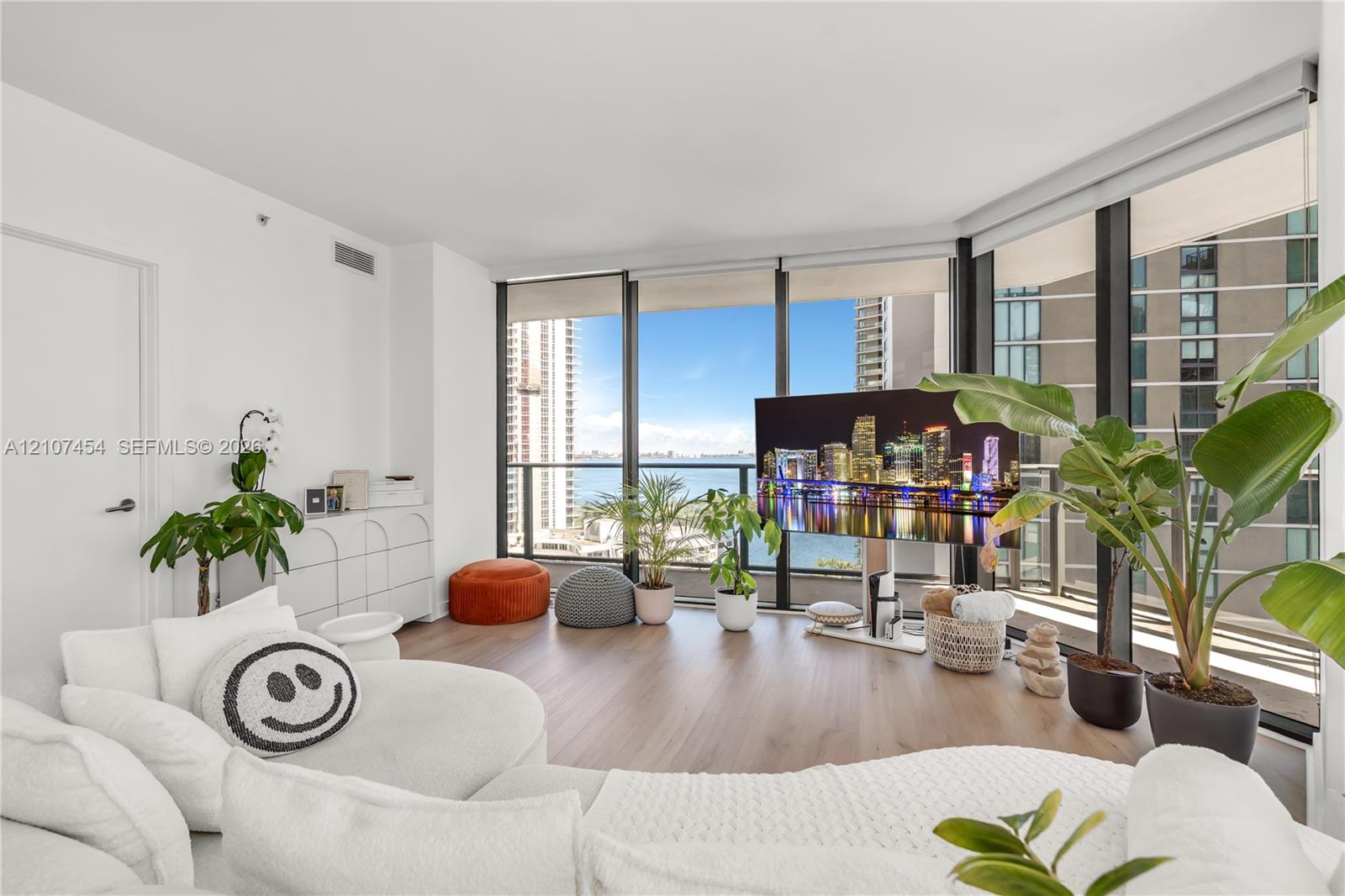 Floor-to-ceiling windows, wood-finish flooring, and an attached balcony with metal railing