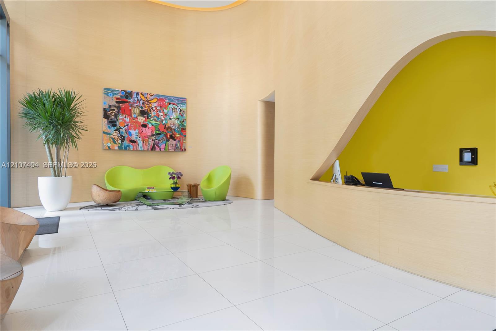 Double-height curved wall with wood-veneer finish, polished tile flooring, and a triangular architectural cutout featuring a built-in counter