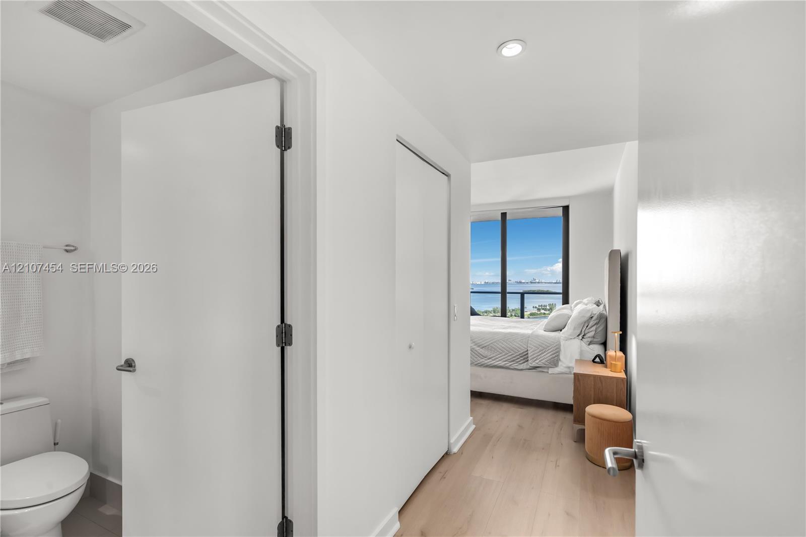Floor-to-ceiling windows with water backdrop, wood-finish flooring, and recessed ceiling lighting