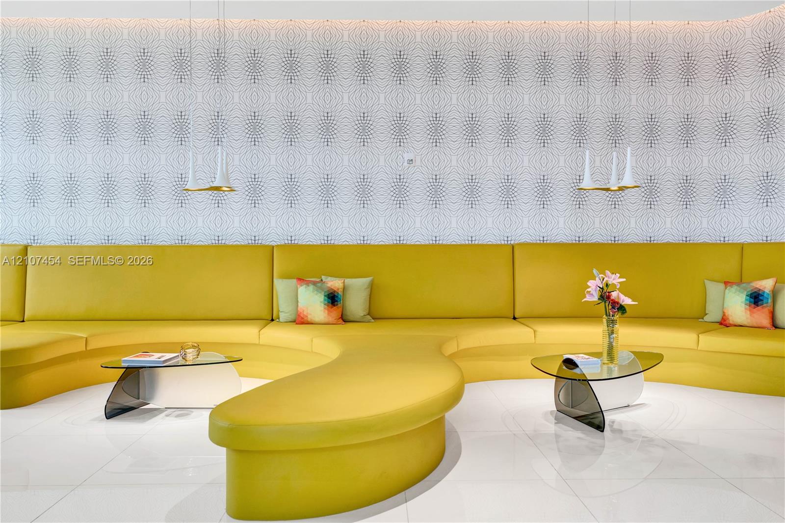 Built-in curved yellow seating, geometric patterned wallpaper, polished tile flooring, and dual hanging pendant lights with gold-tone accents