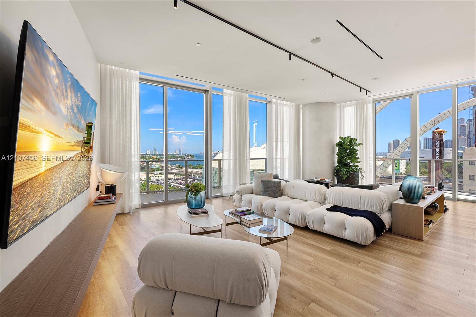 Floor-to-ceiling windows, wood-finish flooring, custom wall-mounted shelving, and recessed track lighting