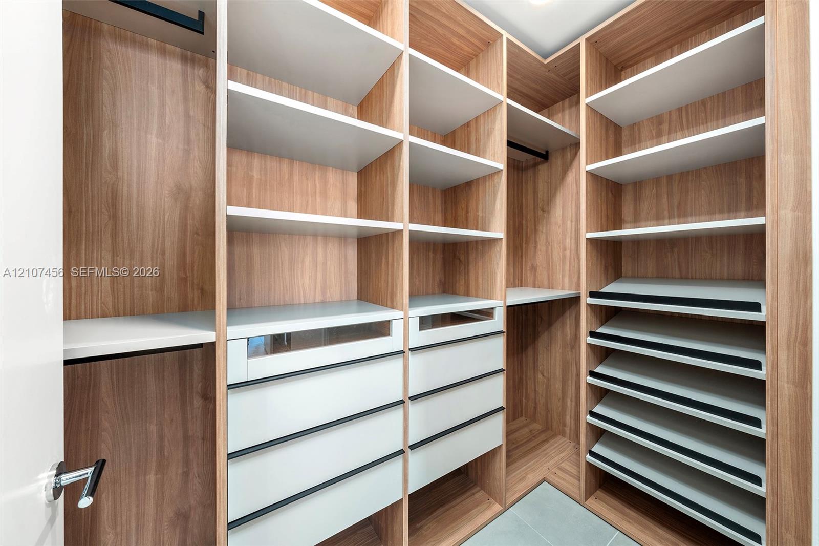 Custom walk-in closet featuring wood-finish cabinetry, built-in shelving, integrated soft-close drawers, angled shoe racks, and hanging rods