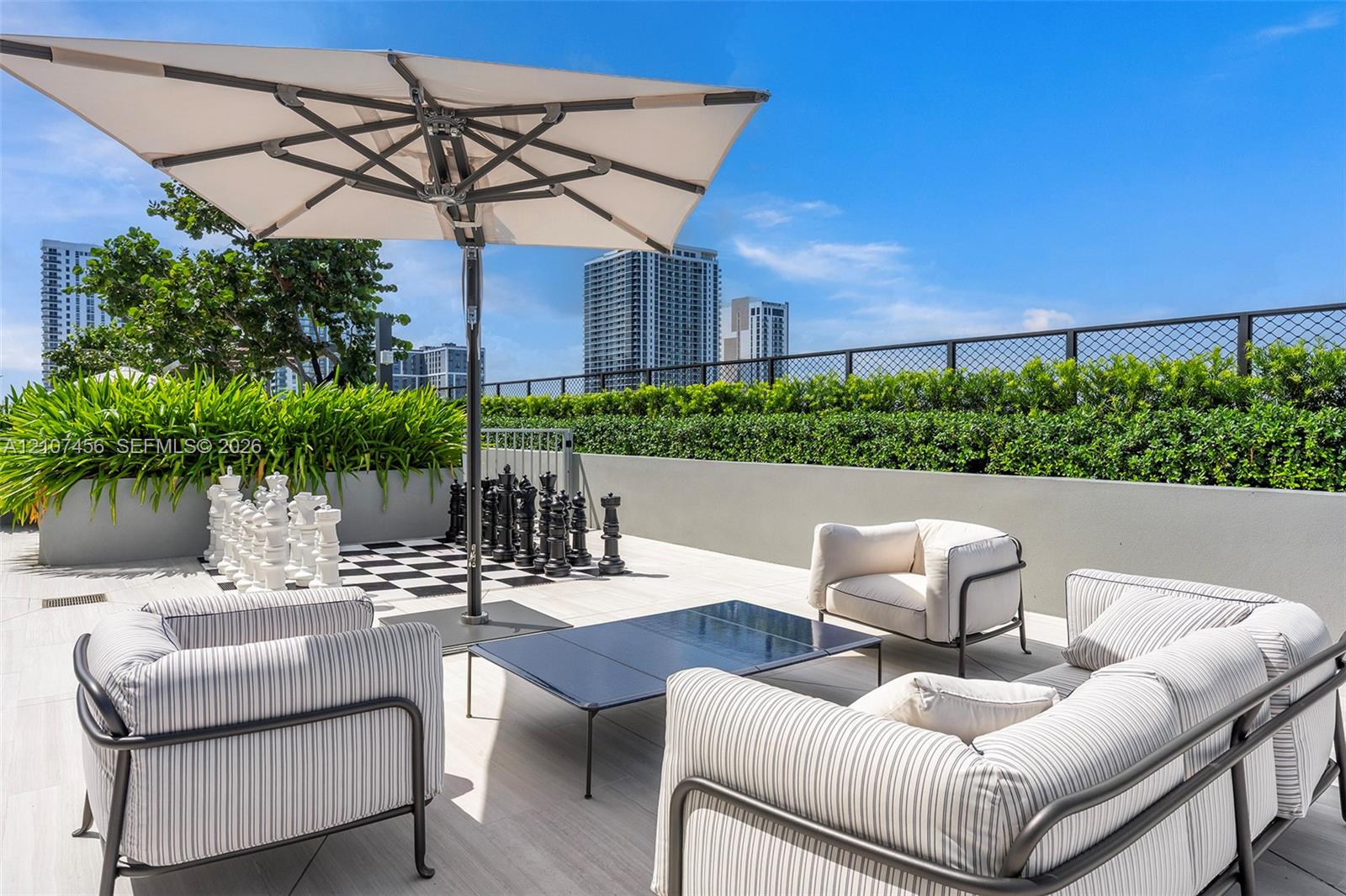 Rooftop terrace featuring large-format tile flooring, a concrete perimeter wall, integrated garden planter boxes, and a metal wire fence