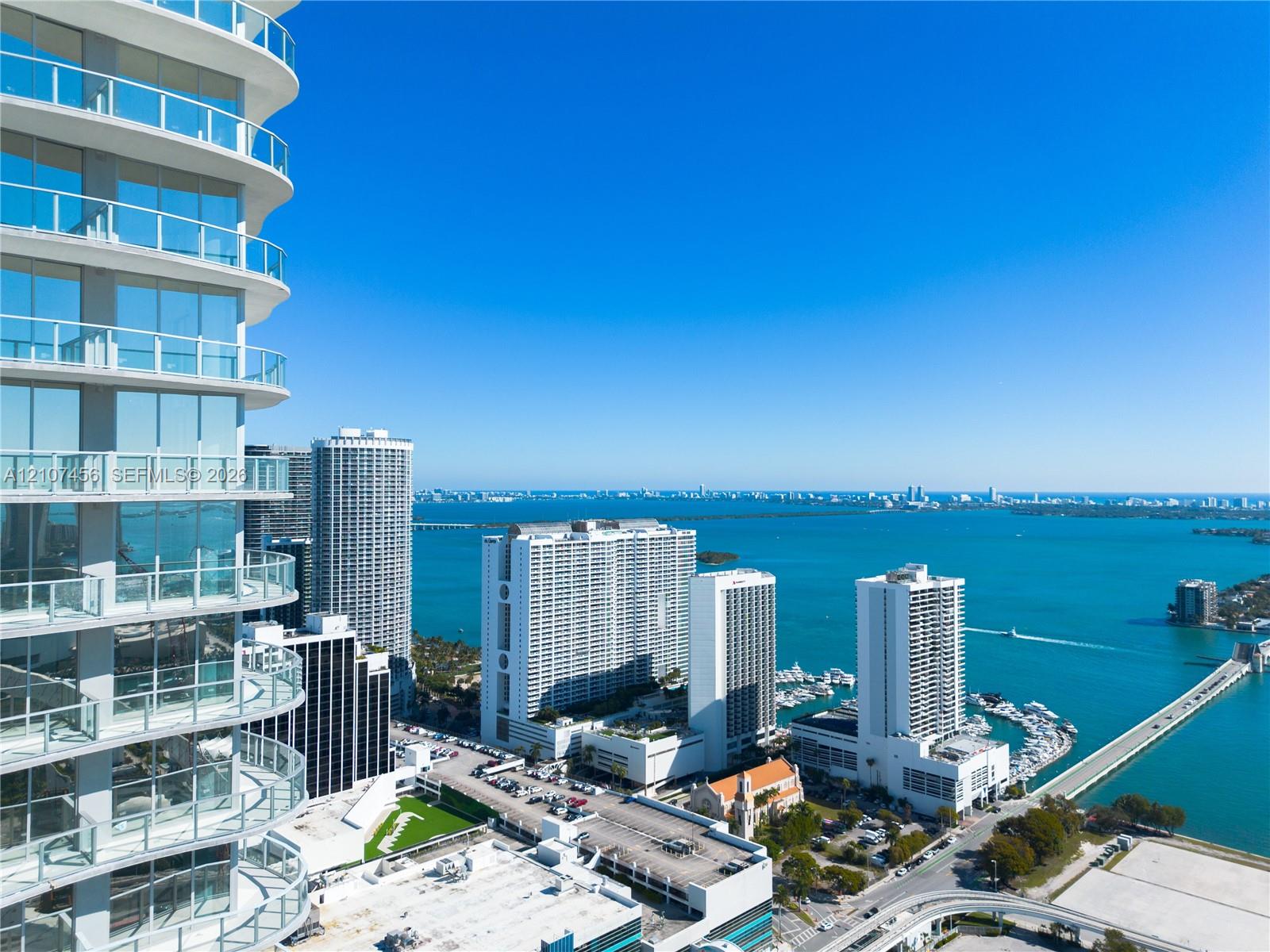 High-rise exterior featuring curved glass facade, wraparound glass-panel balconies, and floor-to-ceiling windows