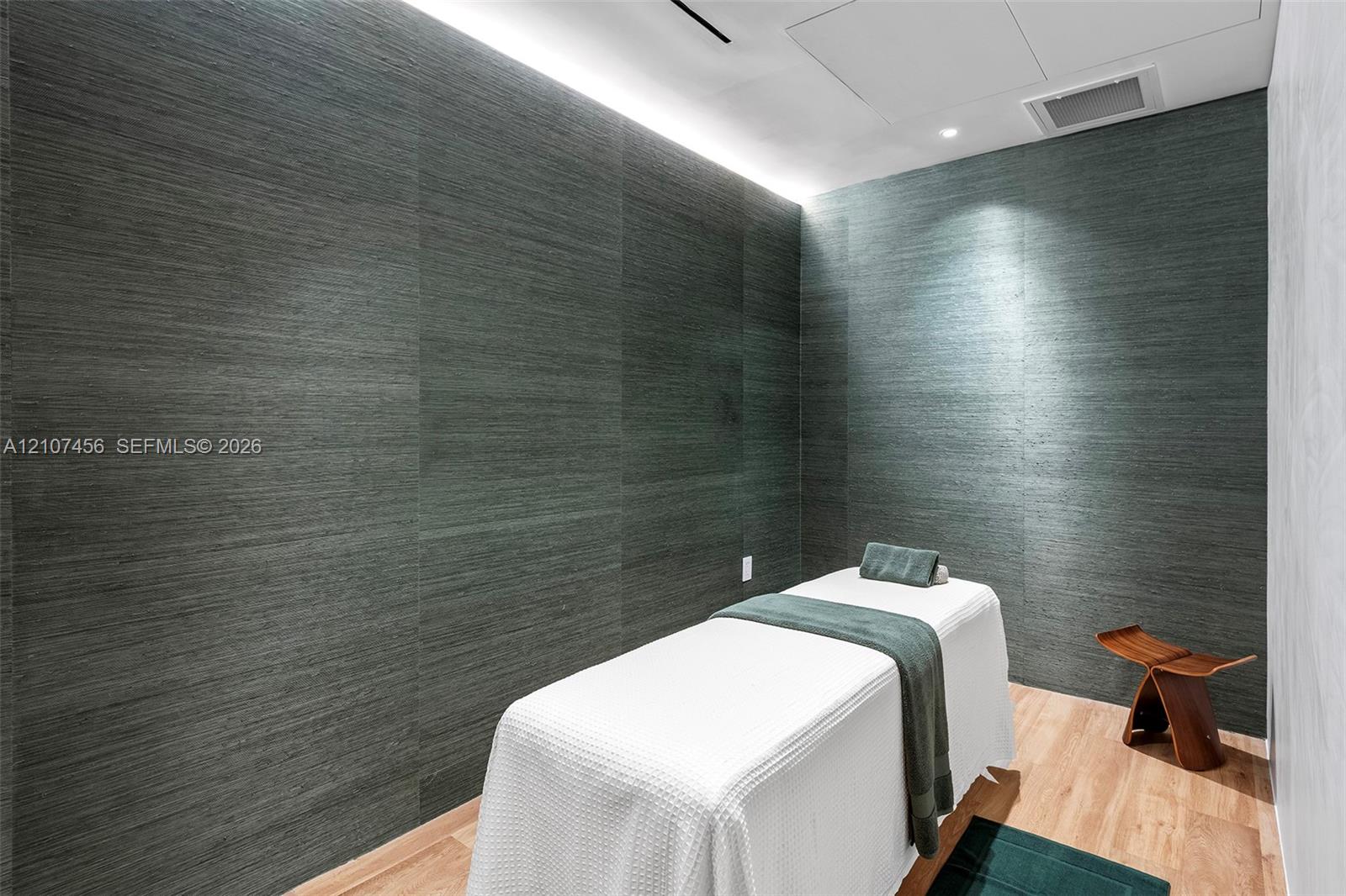 Textured dark-toned wall paneling featuring integrated cove lighting and wood-finish flooring