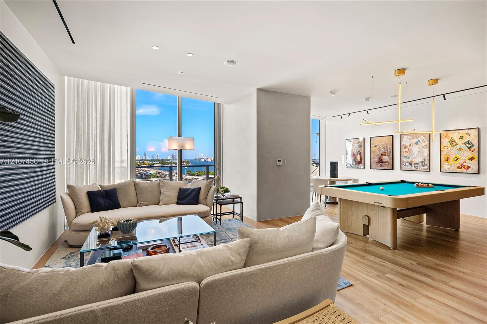 Floor-to-ceiling windows, wood-finish flooring, recessed lighting, and contemporary gold-finish geometric pendant lighting