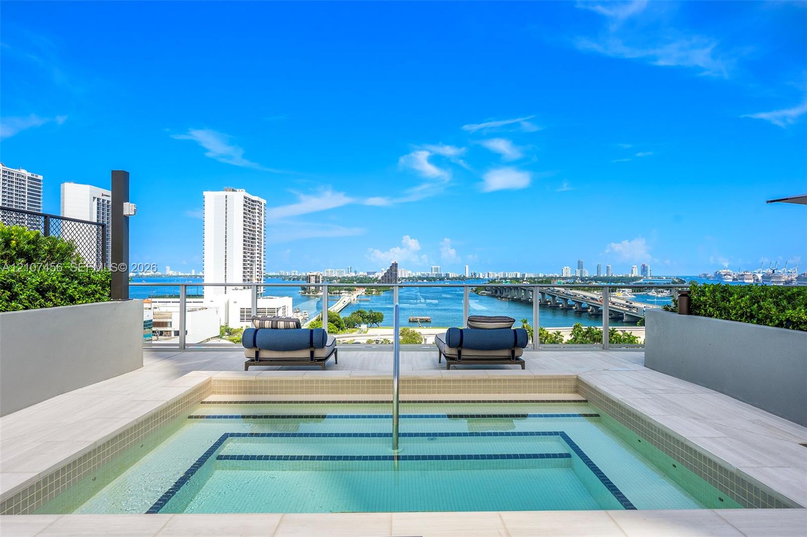Rooftop terrace featuring an in-ground spa, tiled deck, metal railing, and integrated landscaping