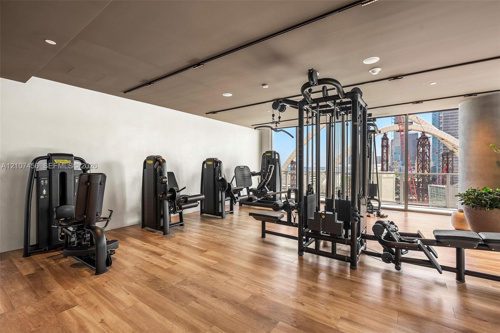 Fitness center featuring wood-finish flooring, floor-to-ceiling windows, and recessed lighting
