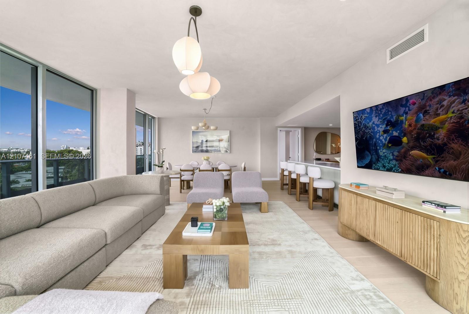 Floor-to-ceiling windows, light-tone wood-finish flooring, recessed lighting, and a kitchen island with stone-finish countertop
