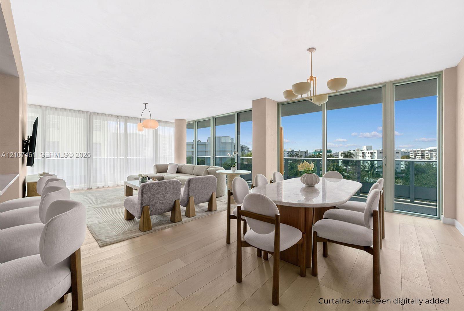 Open-concept living space featuring wood-finish flooring, floor-to-ceiling glass panel walls, and multiple tiered pendant light fixtures