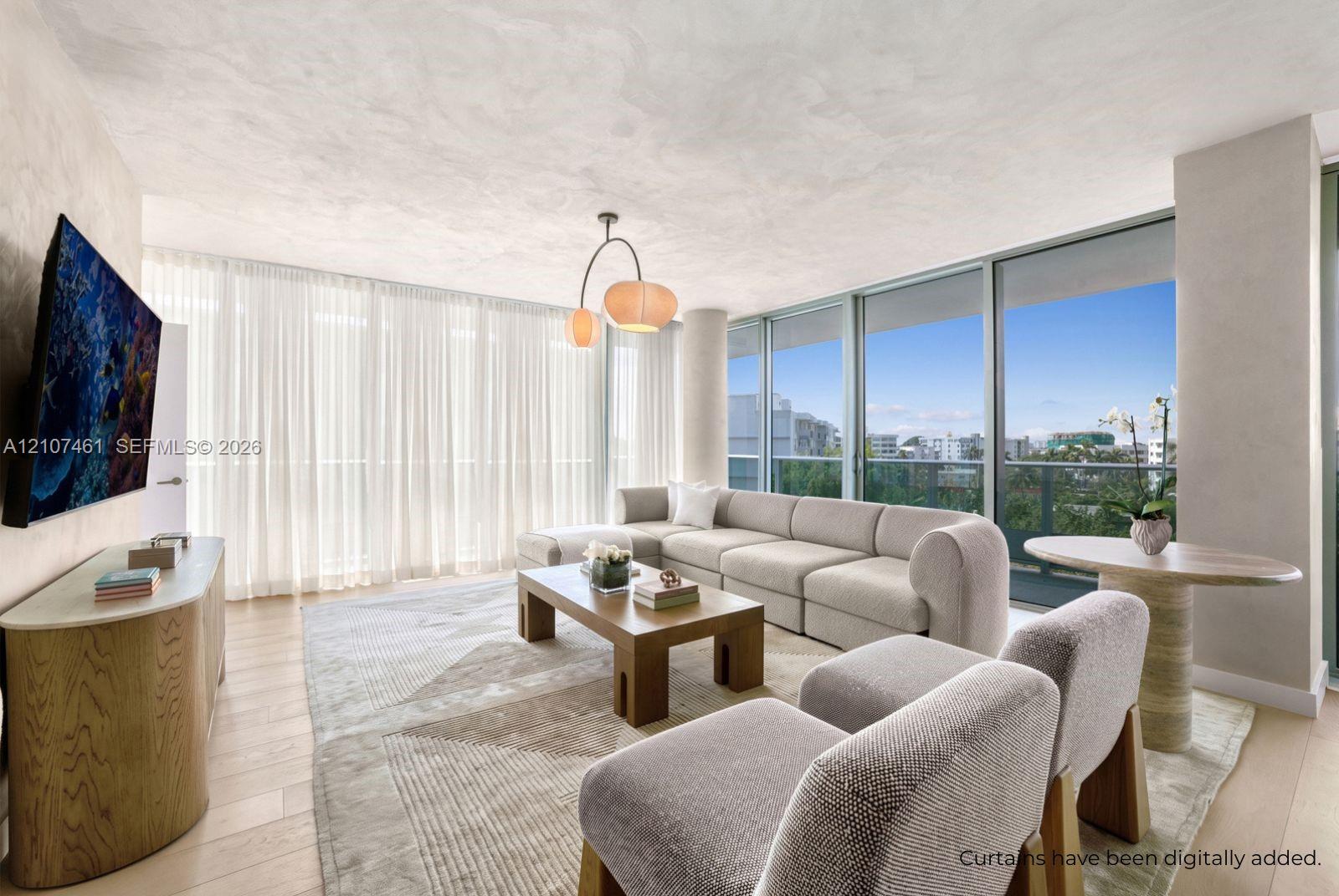 Living space featuring floor-to-ceiling glass paneling, wood-finish flooring, custom textured wall finishes, and a multi-pendant light fixture