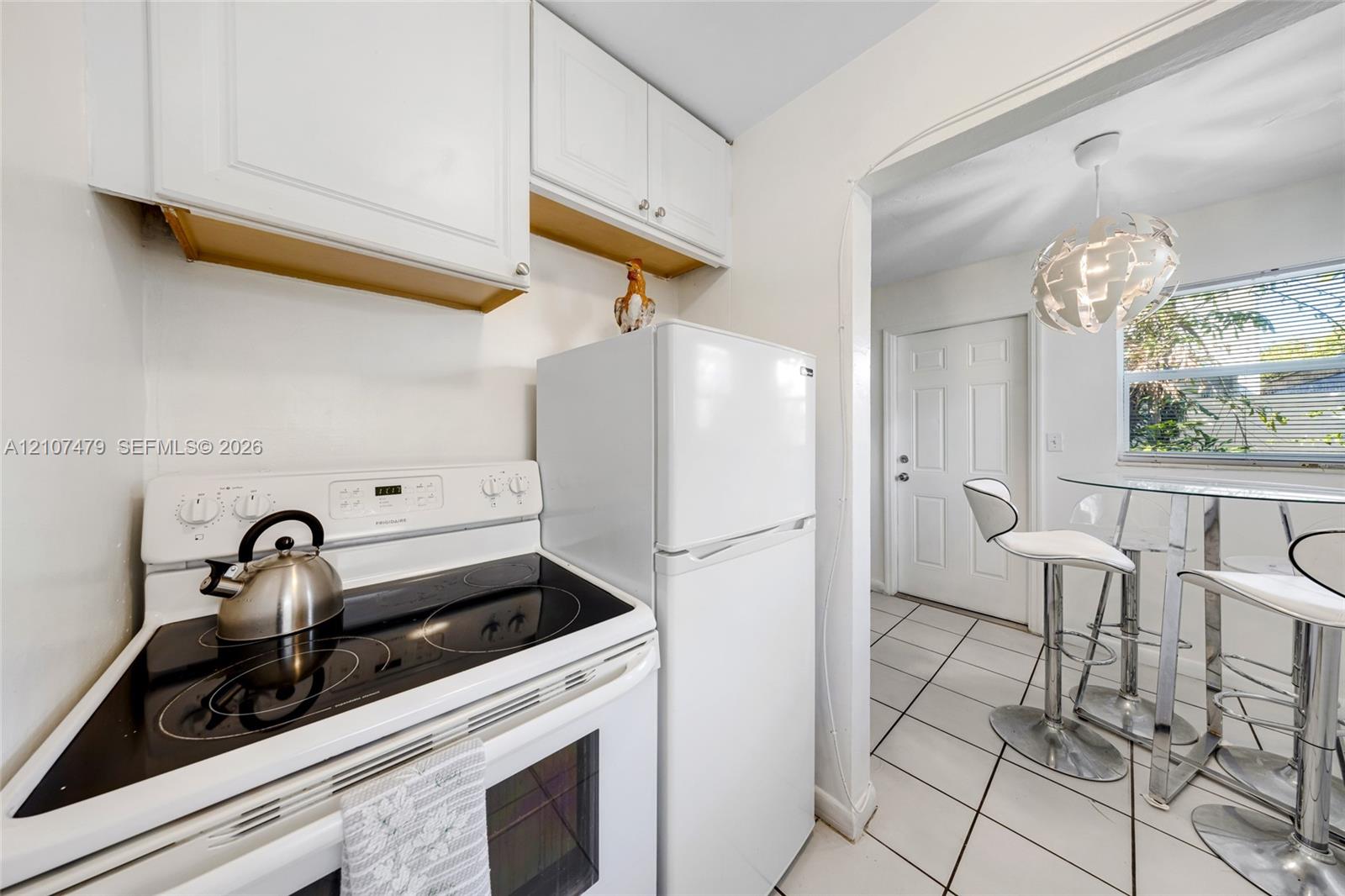 Kitchen featuring white cabinetry, glass-top electric range, white refrigerator, and ceramic tile flooring
