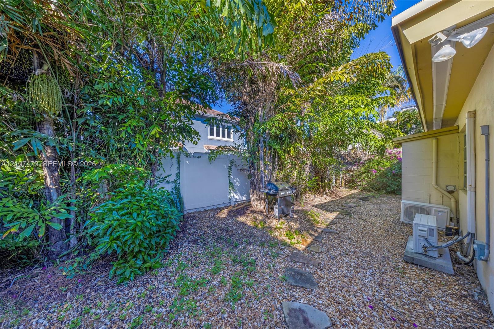 Side yard area featuring gravel ground cover, natural stone paver pathway, and mature tree landscaping