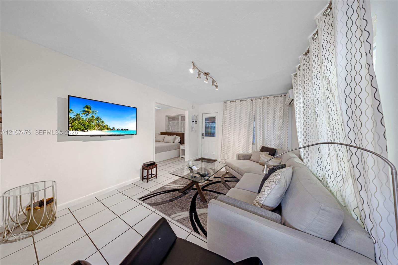 Bright living area featuring ceramic tile flooring, neutral wall tones, and track lighting