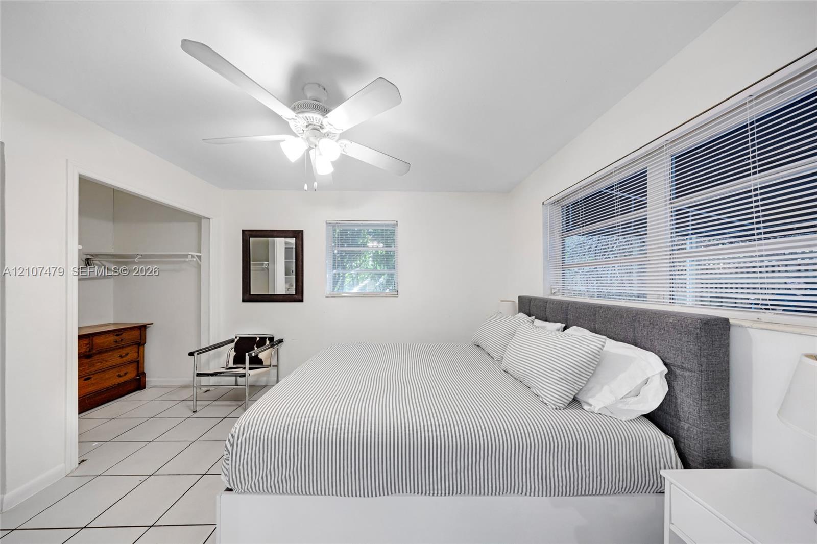Interior space featuring white ceramic tile flooring, a multi-blade ceiling fan with integrated lighting, and horizontal window blinds