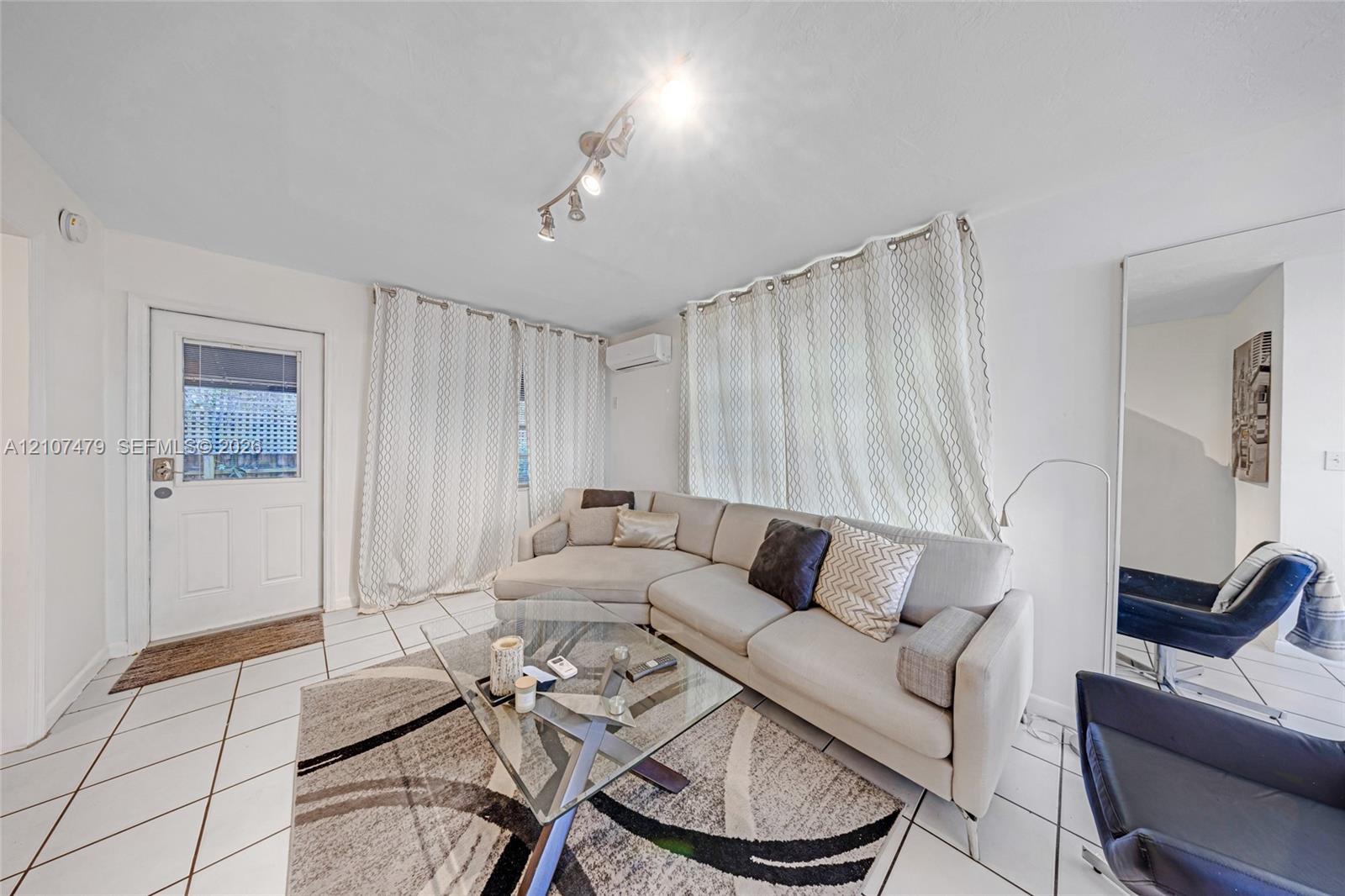 Interior space featuring white tiled flooring, a mounted ductless mini-split HVAC unit, and track lighting